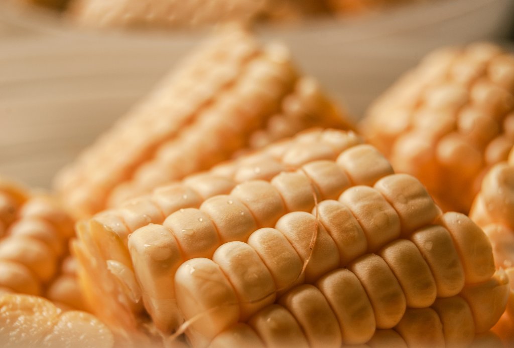 A pile of corn on the cobs in a light brown bowl